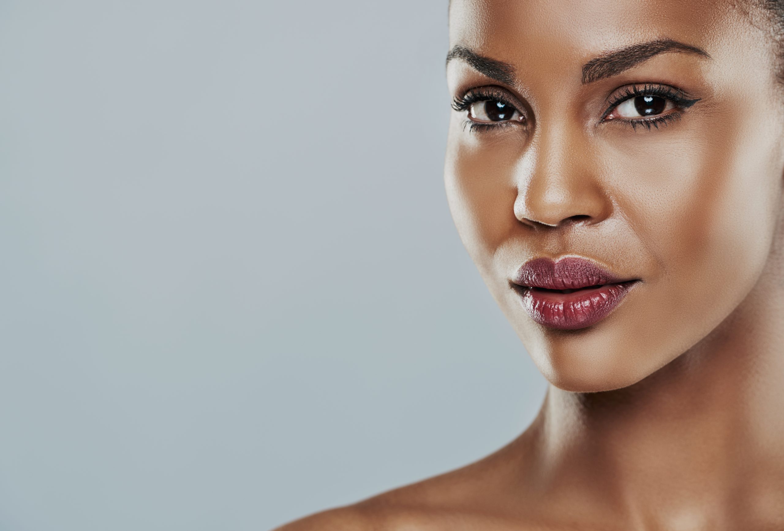 Beautiful young woman with perfect skin against a gray background